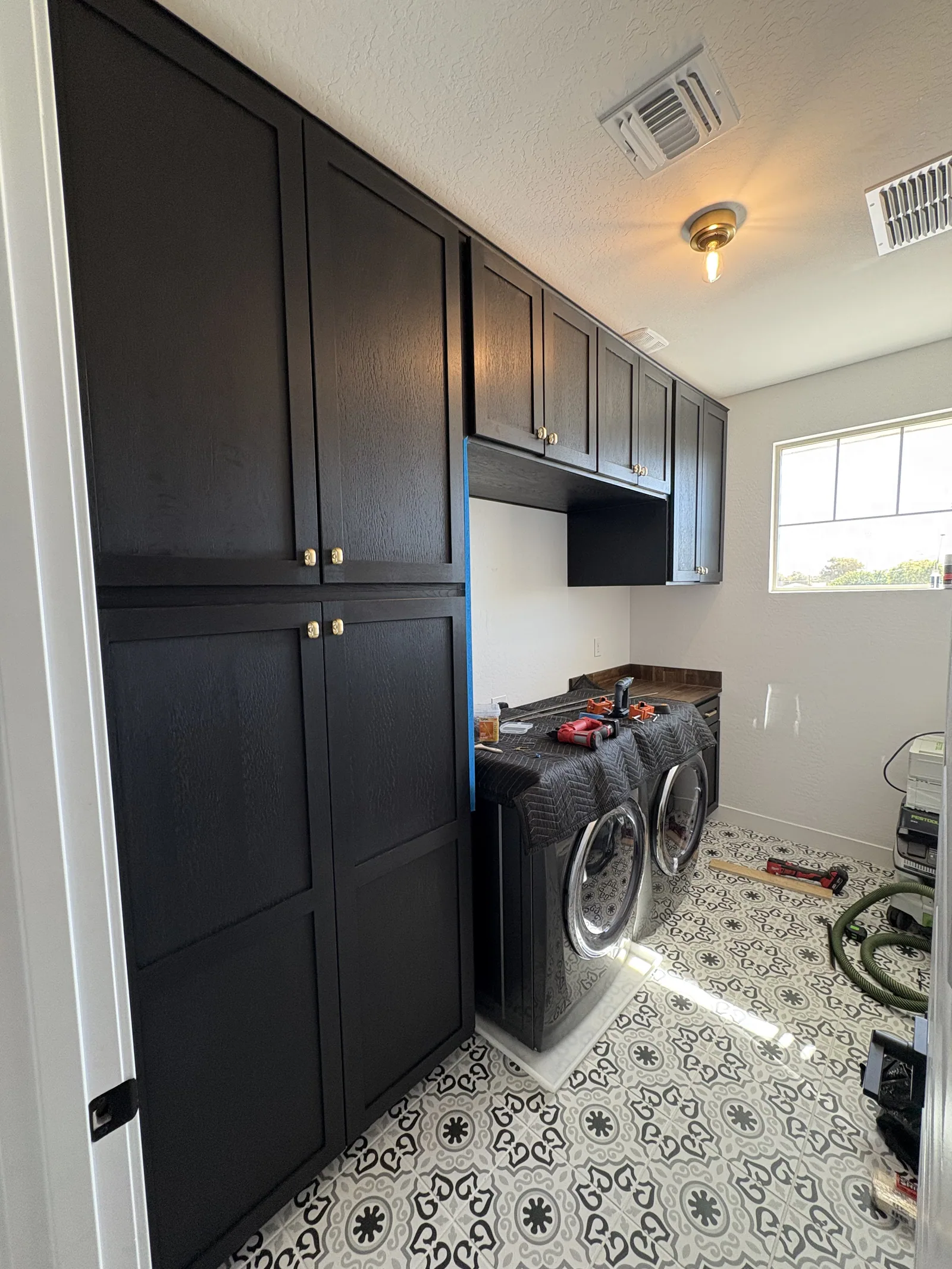 Dark laundry built-in with upper cabinets and wood worktop