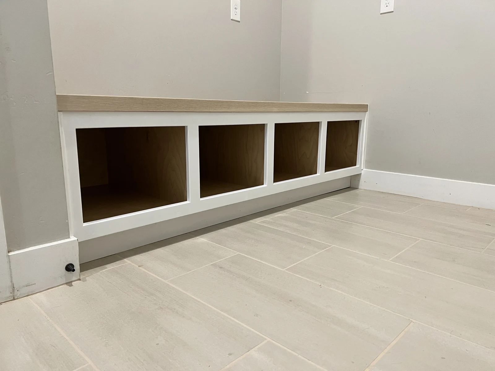 Custom white mudroom built-in with a natural wood bench